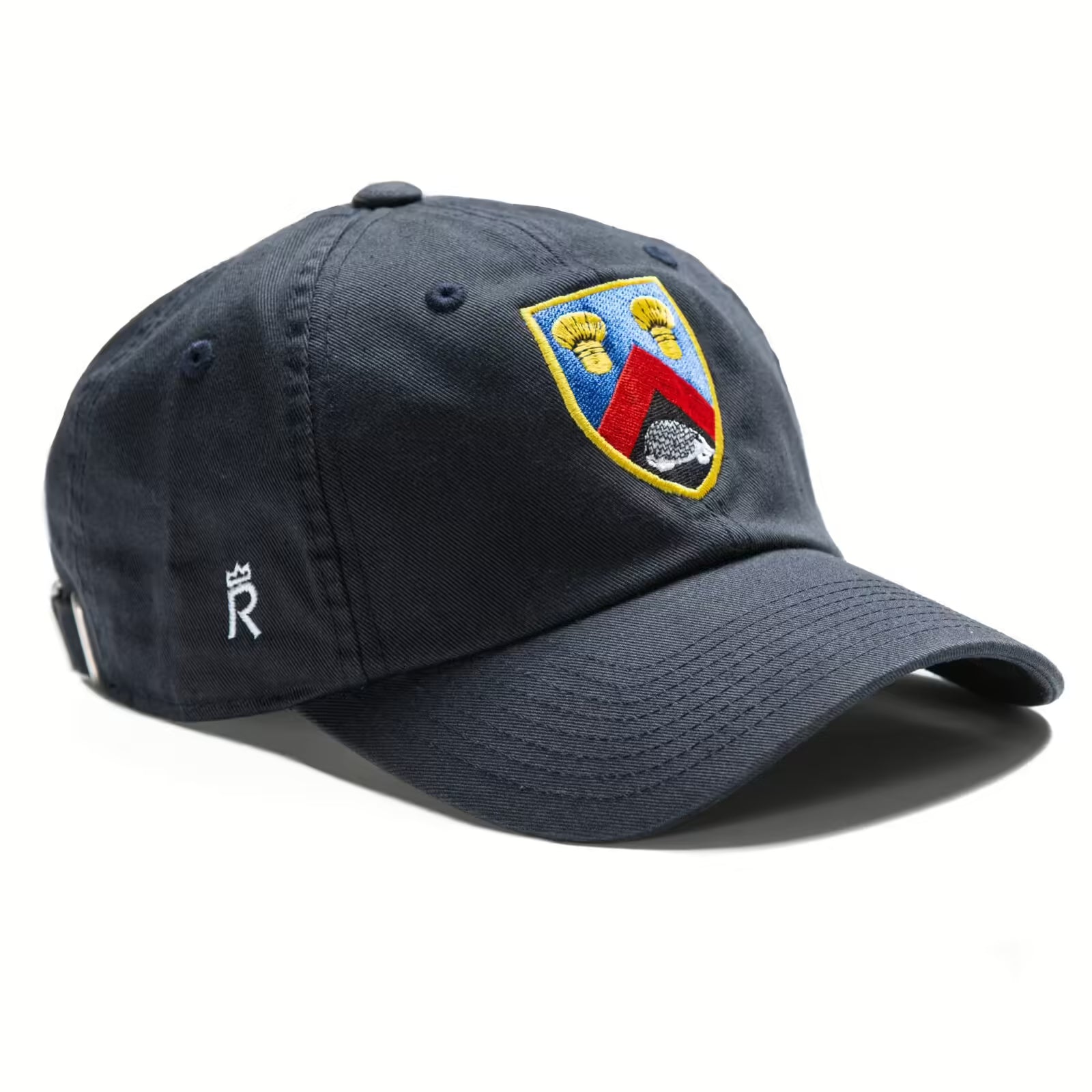 Rex Club | The Alderley Edge CC Slouch by Rex Club is a navy blue 100% cotton cap with a colorful embroidered crest on the front and a small white "R" with crown on the side, inspired by the classic Cheshire countryside charm. | Custom Caps | Custom Hats | Team Headwear | UK