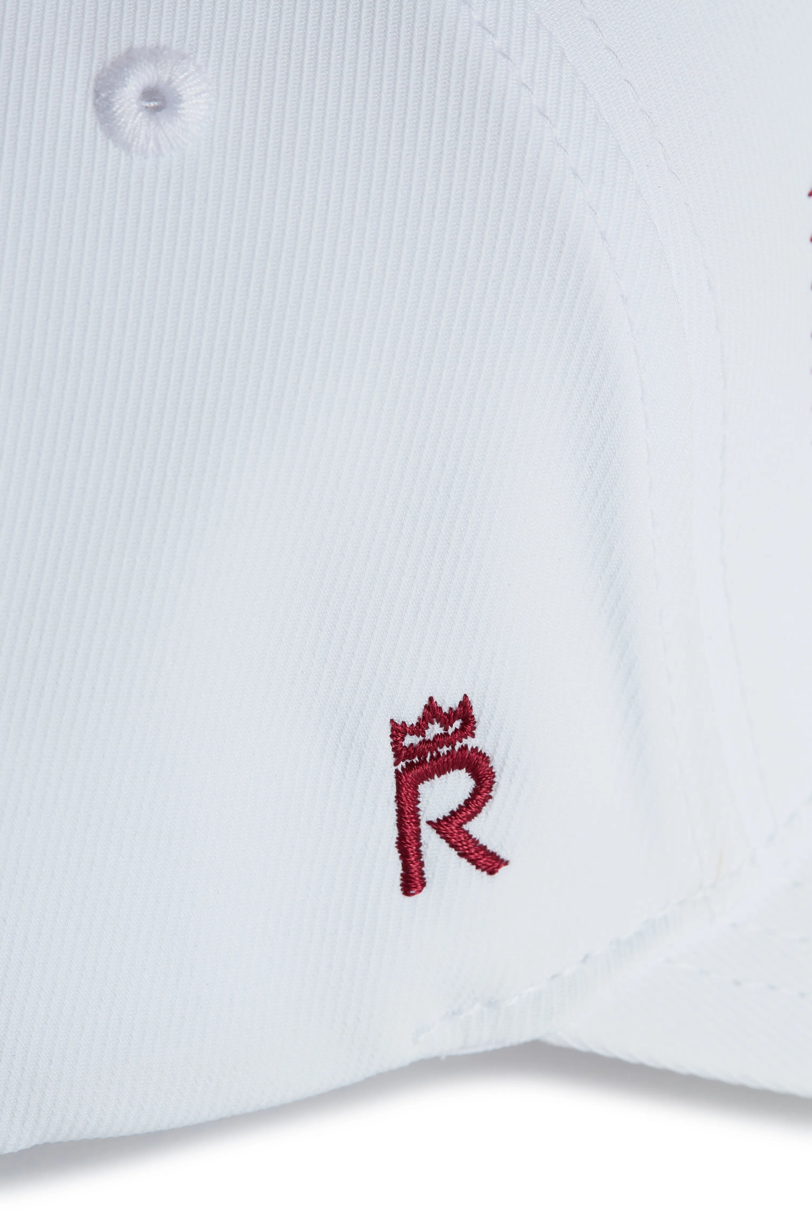 Rex Club | Close-up of a white performance cap from Rex Club, featuring a small maroon "R" with a crown symbol embroidered above it—perfect for fans of the OFFSEASON 26 - Navy collection seeking stylish headwear. | Custom Caps | Custom Hats | Team Headwear | UK