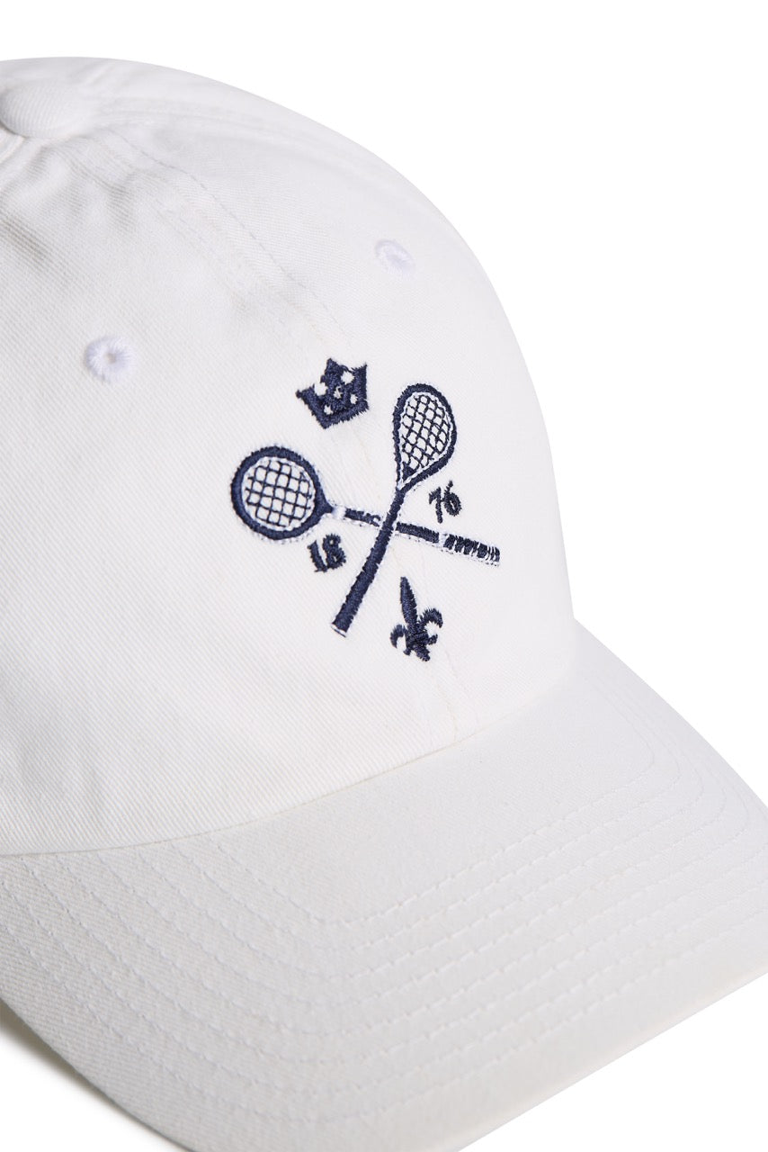 Rex Club | The Rex Club MTRC – White baseball cap features an embroidered design of two crossed tennis rackets, a small crown, “1876,” and a fleur-de-lis in navy blue on the front—a stylish piece of club merchandise perfect for fans of classic sportswear or collectors of Manchester Tennis & Racquets Club caps. | Custom Caps | Custom Hats | Team Headwear | UK