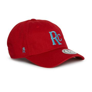 Rex Club | The RC 26 Slouch by Rex Club is a red monogram cap with blue "Rc" lettering on the front, a small crown logo on the side, and a circular sticker on the brim, inspired by classic Rex Club style. | Custom Caps | Custom Hats | Team Headwear | UK