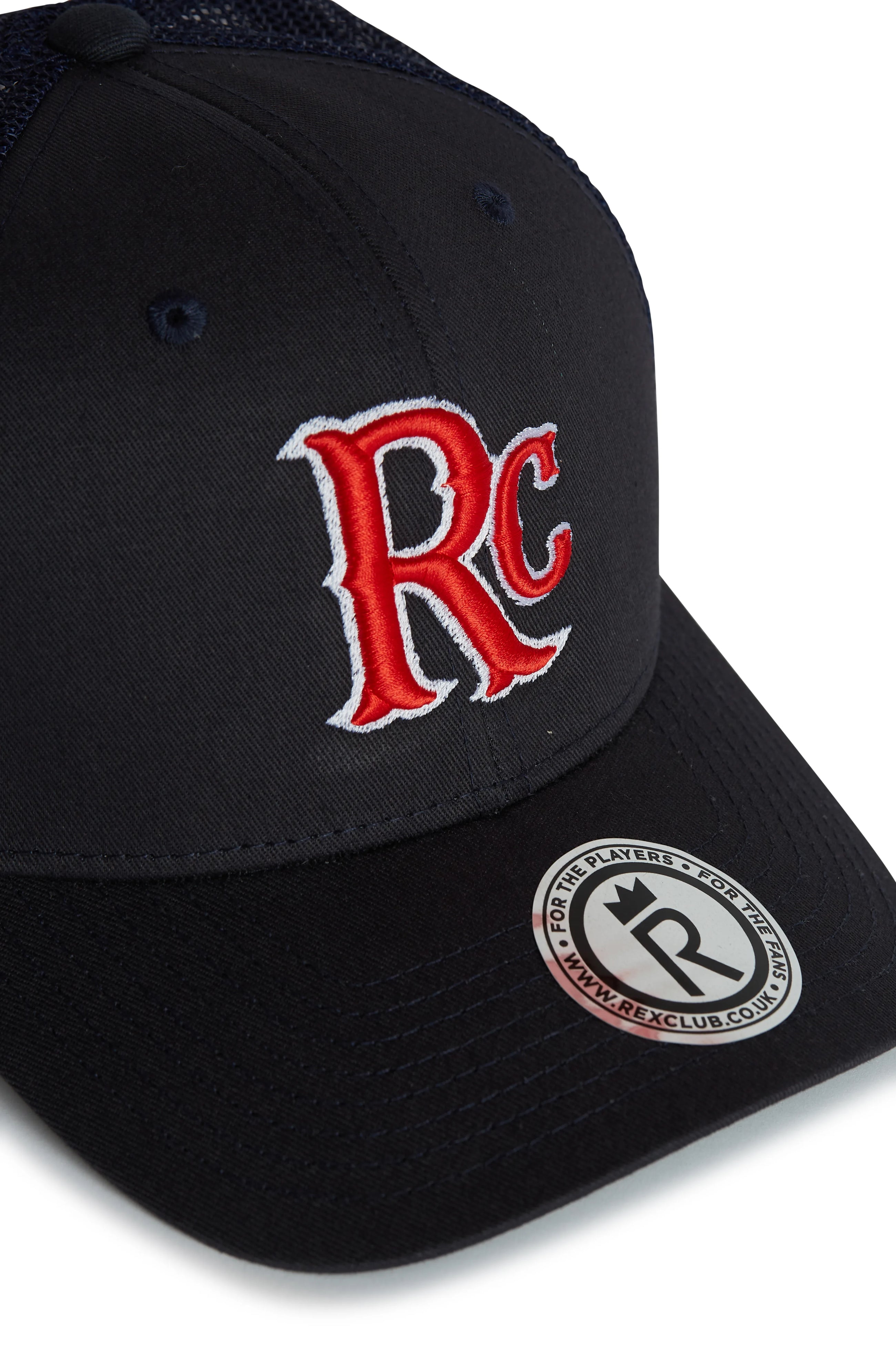 Rex Club | The RC 26 Trucker by Rex Club is a black hat with a bold red and white "RC" sport monogram embroidered on the front and a round Rex Club logo sticker with website on the brim. | Custom Caps | Custom Hats | Team Headwear | UK