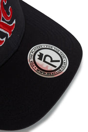 Rex Club | A close-up of the black RC 26 Trucker hat by Rex Club, featuring red embroidery, a sticker on the brim with “FOR THE PLAYERS • FOR THE FANS” and “WWW.REXCLUB.COM,” and a sport team "R" monogram with an arrow. | Custom Caps | Custom Hats | Team Headwear | UK