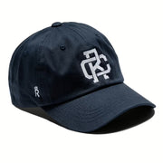 Rex Club | The Rex Club Monogram is a navy blue 100% cotton baseball cap with an interlocking white embroidered logo on the front and a small white crown with "R" emblem on the side. | Custom Caps | Custom Hats | Team Headwear | UK