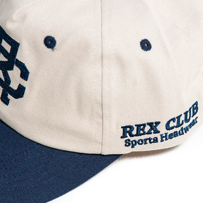 Rex Club | The Rex Club - TwoTone - Canvas Cap is a beige 100% cotton cap with a navy blue brim, navy eyelets, and "REX CLUB Sports Headwear" embroidery plus partial "RC" initials. One size fits most. | Custom Caps | Custom Hats | Team Headwear | UK