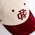Rex Club | The Rex Club RC - Victor - Two Tone is a cream and maroon cotton baseball cap with embroidered maroon lettering, leaf designs on the brim, two maroon vents on the cream section, and an adjustable strap for a one size fits most fit. | Custom Caps | Custom Hats | Team Headwear | UK