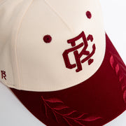 Rex Club | The Rex Club RC - Victor - Two Tone is a cream and maroon cotton baseball cap with embroidered maroon lettering, leaf designs on the brim, two maroon vents on the cream section, and an adjustable strap for a one size fits most fit. | Custom Caps | Custom Hats | Team Headwear | UK