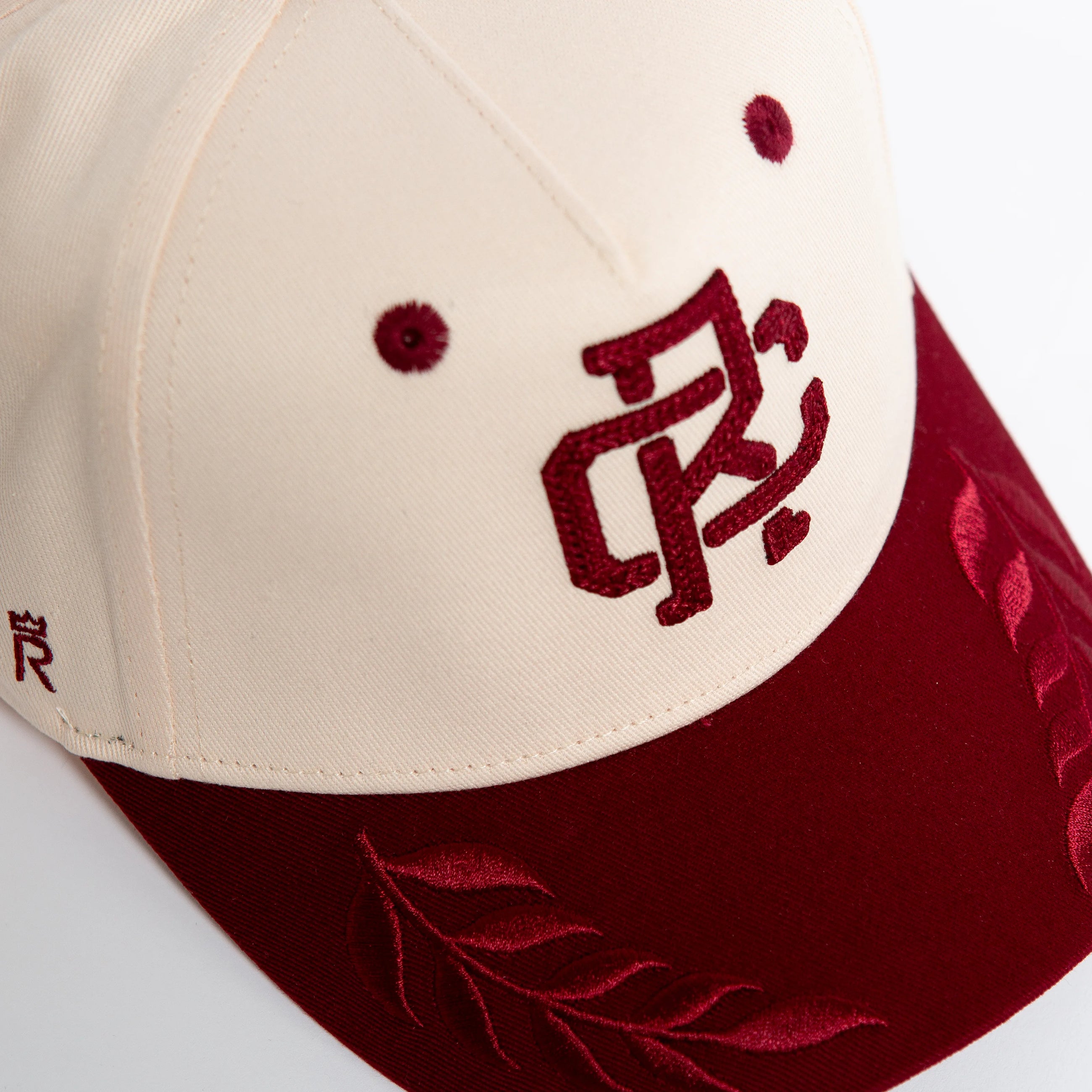 Rex Club | The Rex Club RC - Victor - Two Tone is a cream and maroon cotton baseball cap with embroidered maroon lettering, leaf designs on the brim, two maroon vents on the cream section, and an adjustable strap for a one size fits most fit. | Custom Caps | Custom Hats | Team Headwear | UK