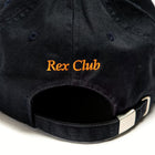 Rex Club | A close-up of the back of a black OFFSEASON 23 Slouch baseball cap by Rex Club, made from 100% cotton, with "Rex Club" embroidered in orange above the adjustable strap and silver buckle. | Custom Caps | Custom Hats | Team Headwear | UK