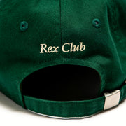 Rex Club | A close-up of the back of a green Rex Club OFFSEASON 23 Slouch cap, made from 100% cotton, with "Rex Club" embroidered in beige above the adjustable strap and metal buckle, highlighting its classic slouch fit. | Custom Caps | Custom Hats | Team Headwear | UK