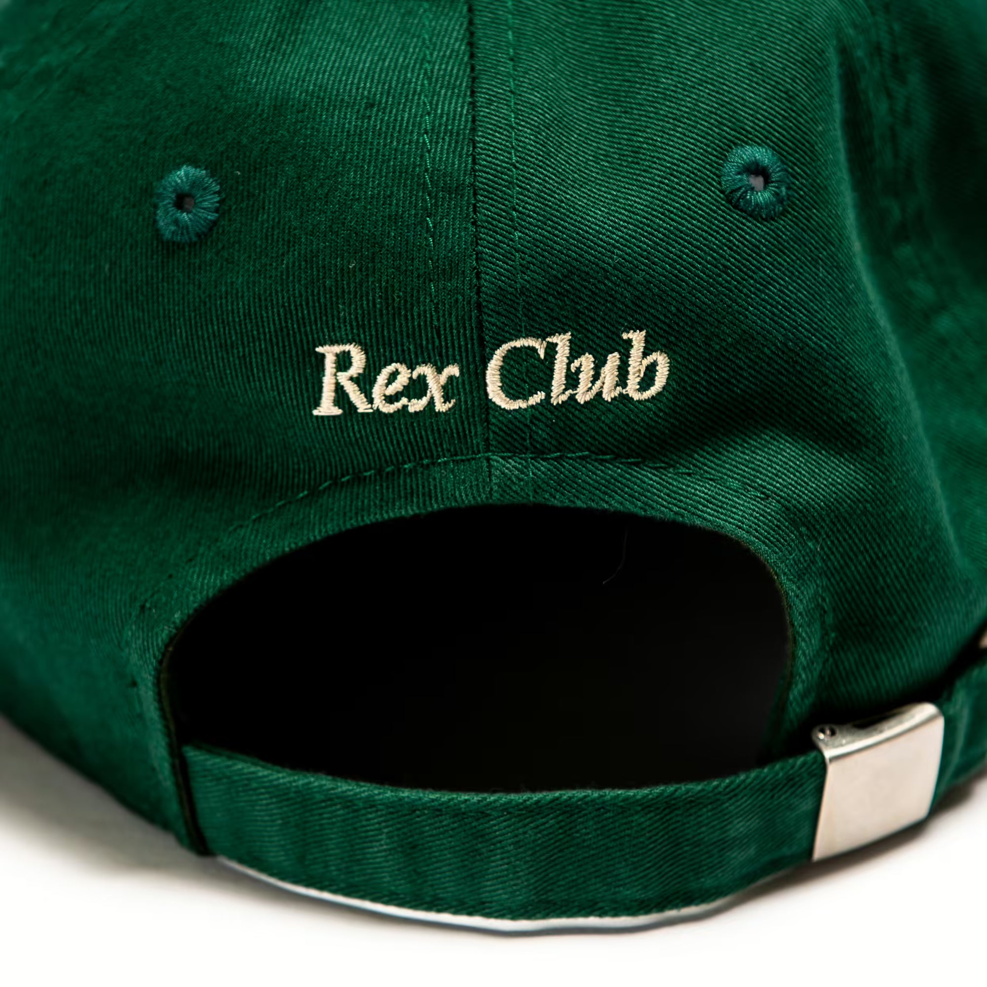 Rex Club | A close-up of the back of a green Rex Club OFFSEASON 23 Slouch cap, made from 100% cotton, with "Rex Club" embroidered in beige above the adjustable strap and metal buckle, highlighting its classic slouch fit. | Custom Caps | Custom Hats | Team Headwear | UK