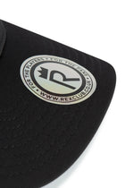 Rex Club | Close-up of the RC 26 Performance black cap by Rex Club, featuring a circular silver and black "R" monogram crown sticker that reads "FOR THE PLAYERS • FOR THE FANS • WWW.REXCLUB.CO.UK." Ideal for sports teams and fans. | Custom Caps | Custom Hats | Team Headwear | UK