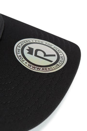 Rex Club | Close-up of the RC 26 Performance black cap by Rex Club, featuring a circular silver and black "R" monogram crown sticker that reads "FOR THE PLAYERS • FOR THE FANS • WWW.REXCLUB.CO.UK." Ideal for sports teams and fans. | Custom Caps | Custom Hats | Team Headwear | UK