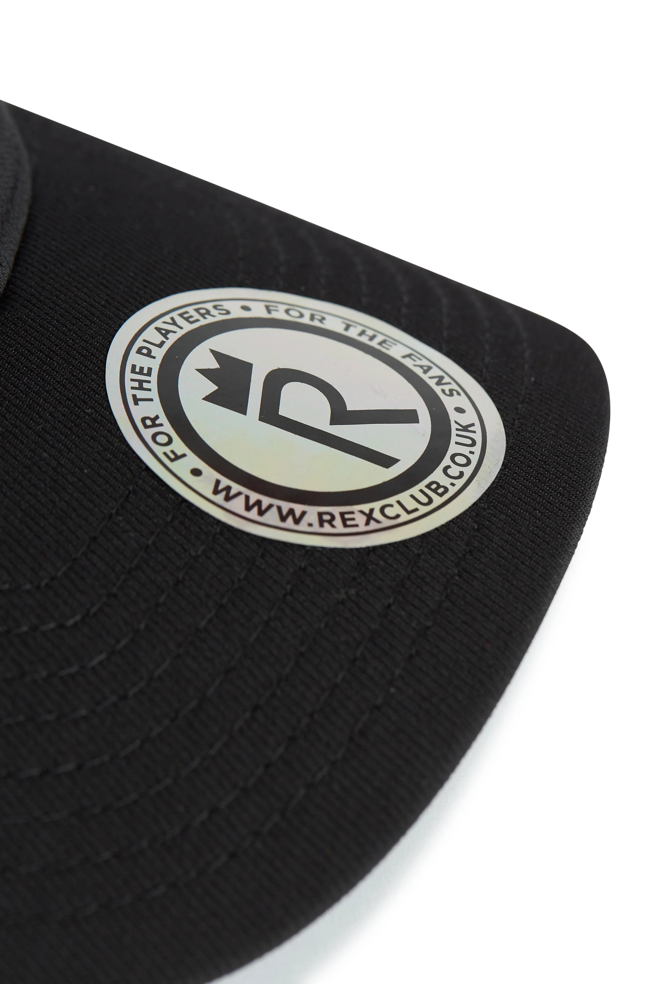 Rex Club | Close-up of the RC 26 Performance black cap by Rex Club, featuring a circular silver and black "R" monogram crown sticker that reads "FOR THE PLAYERS • FOR THE FANS • WWW.REXCLUB.CO.UK." Ideal for sports teams and fans. | Custom Caps | Custom Hats | Team Headwear | UK