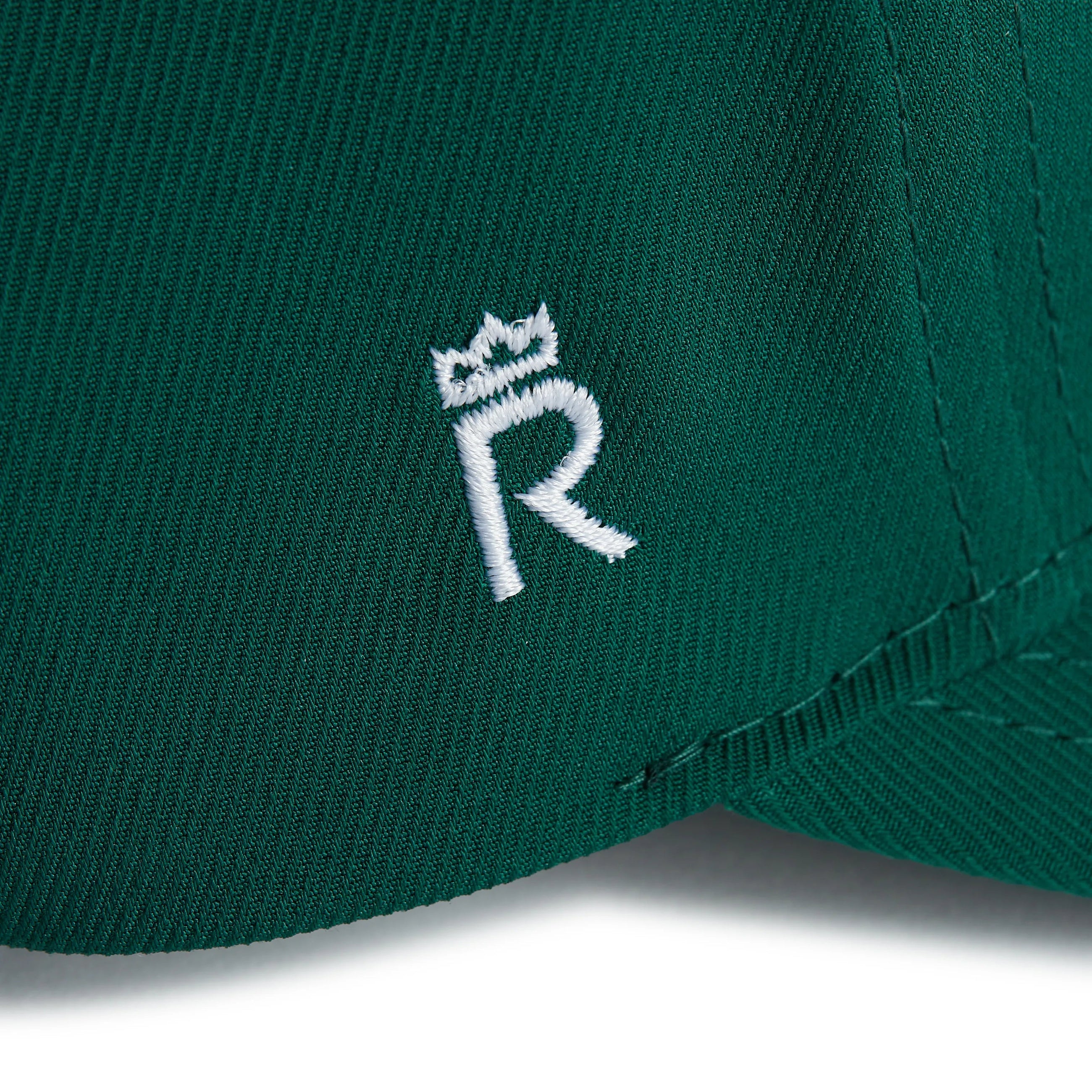 Rex Club | Close-up of the green RC 26 Performance jersey fabric by Rex Club, featuring a white embroidered "R" topped with a crown—a stylish, sporty monogram detail. | Custom Caps | Custom Hats | Team Headwear | UK
