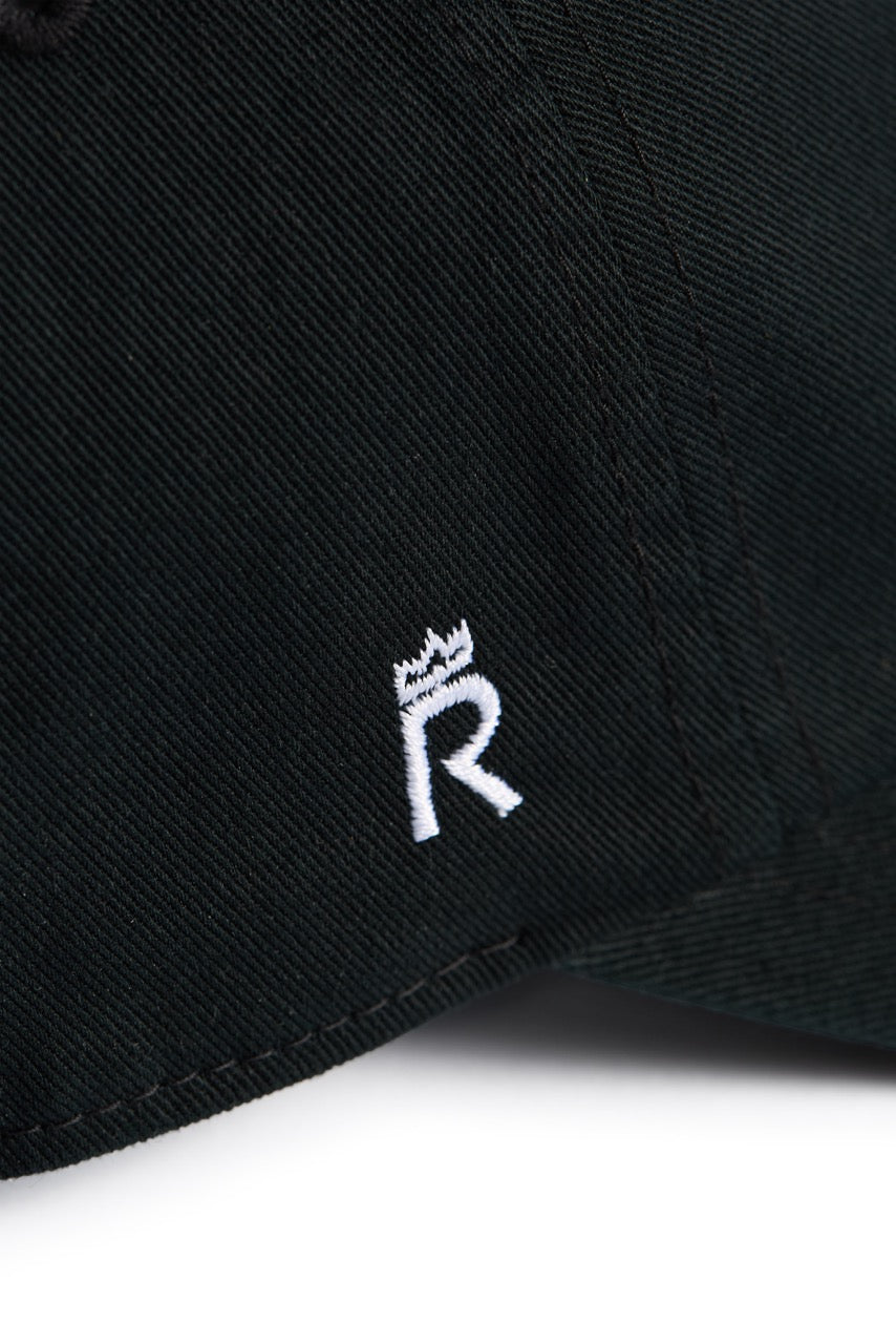 Rex Club | A close-up of the Rex Club Labor Et Ludus cap, crafted from 100% black cotton fabric and featuring a small white embroidered crowned “R” emblem. One size fits most. | Custom Caps | Custom Hats | Team Headwear | UK