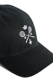 Rex Club | The Rex Club MTRC - Black cap showcases white embroidered details, including two crossed tennis rackets, the numbers 18 and 76, a crown above, and a fleur-de-lis below—seen from an angle on a white background—making it ideal official club merchandise for any enthusiast. | Custom Caps | Custom Hats | Team Headwear | UK