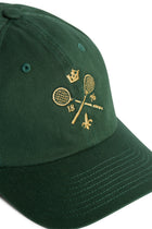Rex Club | A green MTRC - Green cap by Rex Club, featuring gold embroidery of two crossed tennis rackets with a crown above, the numbers 18 and 76 on either side, and a small fleur-de-lis below. | Custom Caps | Custom Hats | Team Headwear | UK