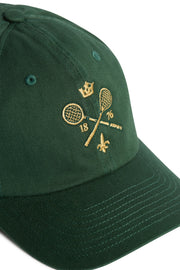 Rex Club | A green MTRC - Green cap by Rex Club, featuring gold embroidery of two crossed tennis rackets with a crown above, the numbers 18 and 76 on either side, and a small fleur-de-lis below. | Custom Caps | Custom Hats | Team Headwear | UK