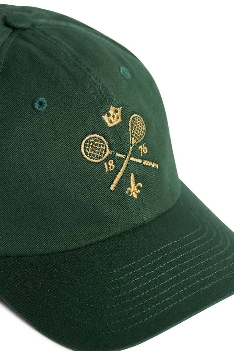 Rex Club | A green MTRC - Green cap by Rex Club, featuring gold embroidery of two crossed tennis rackets with a crown above, the numbers 18 and 76 on either side, and a small fleur-de-lis below. | Custom Caps | Custom Hats | Team Headwear | UK