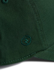 Rex Club | Close-up of the MTRC - Green club cap by Rex Club, crafted from dark green cotton and featuring a small embroidered circle logo with a lightning bolt near the brim—a refined detail that distinguishes this cap. | Custom Caps | Custom Hats | Team Headwear | UK