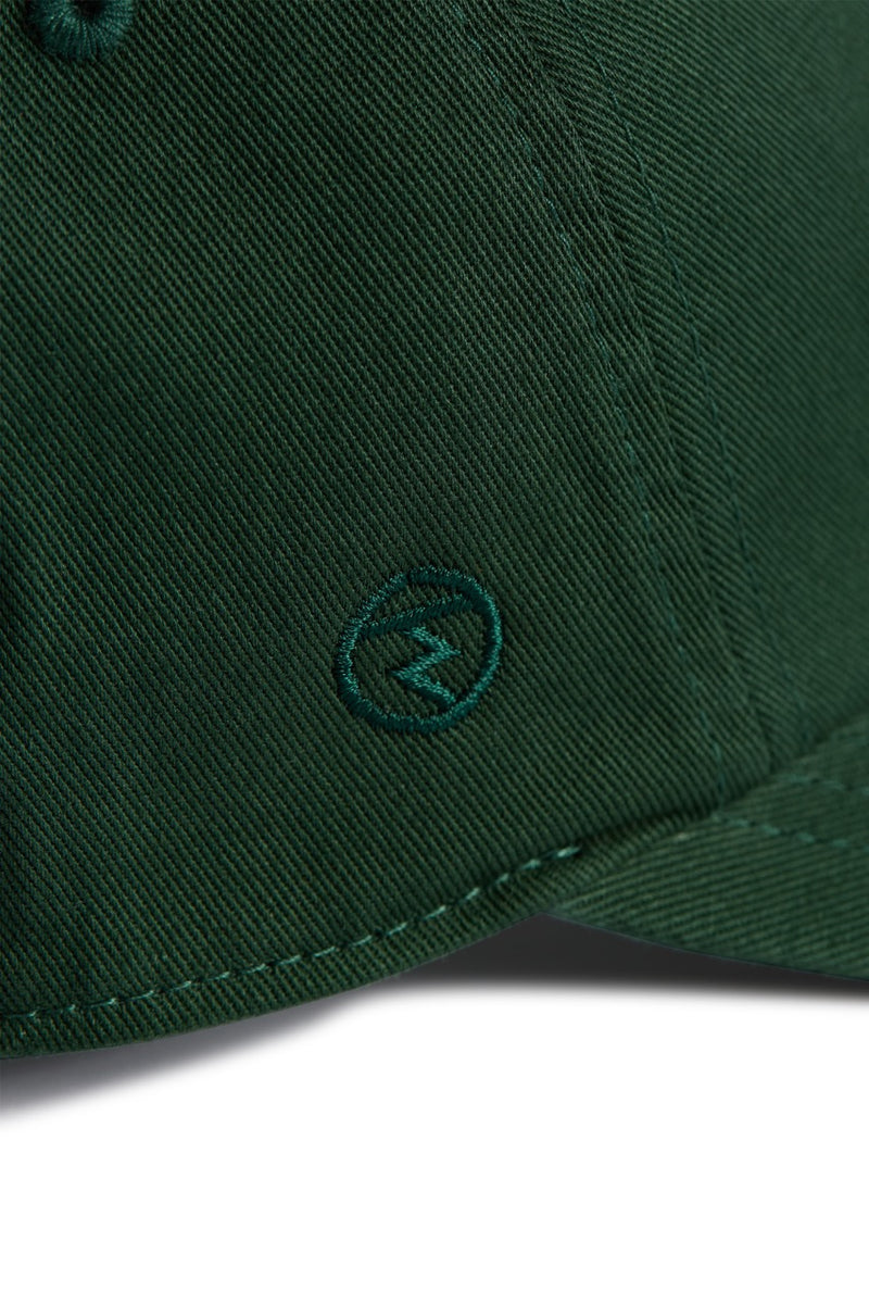 Rex Club | Close-up of the MTRC - Green club cap by Rex Club, crafted from dark green cotton and featuring a small embroidered circle logo with a lightning bolt near the brim—a refined detail that distinguishes this cap. | Custom Caps | Custom Hats | Team Headwear | UK