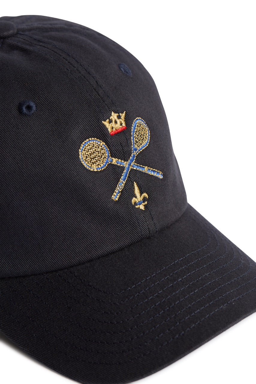 Rex Club | A close-up of a navy Rex Club MTRC cap featuring embroidered gold lacrosse sticks crossed, a gold crown above, and a small gold fleur-de-lis below the sticks—perfect for fans of Manchester Tennis & Racquets Club caps and discerning club merchandise collectors. | Custom Caps | Custom Hats | Team Headwear | UK