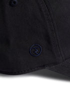Rex Club | Close-up of a navy blue MTRC - Navy cap by Rex Club, featuring a small embroidered circular logo on the side of the brim—ideal for fans seeking official Manchester Tennis & Racquets Club merchandise for their collection. | Custom Caps | Custom Hats | Team Headwear | UK