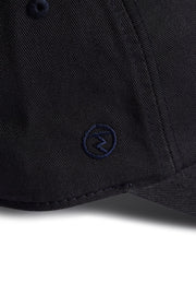 Rex Club | Close-up of a navy blue MTRC - Navy cap by Rex Club, featuring a small embroidered circular logo on the side of the brim—ideal for fans seeking official Manchester Tennis & Racquets Club merchandise for their collection. | Custom Caps | Custom Hats | Team Headwear | UK