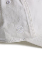 Rex Club | A close-up of the MTRC - White cap by Rex Club highlights its textured fabric and detailed stitching. Featuring a small, circular embroidered logo near the brim, this cap stands out as a distinctive piece of Manchester Tennis & Racquets Club merchandise. | Custom Caps | Custom Hats | Team Headwear | UK