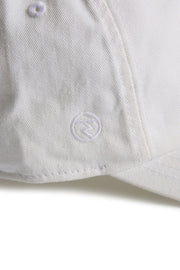 Rex Club | A close-up of the MTRC - White cap by Rex Club highlights its textured fabric and detailed stitching. Featuring a small, circular embroidered logo near the brim, this cap stands out as a distinctive piece of Manchester Tennis & Racquets Club merchandise. | Custom Caps | Custom Hats | Team Headwear | UK