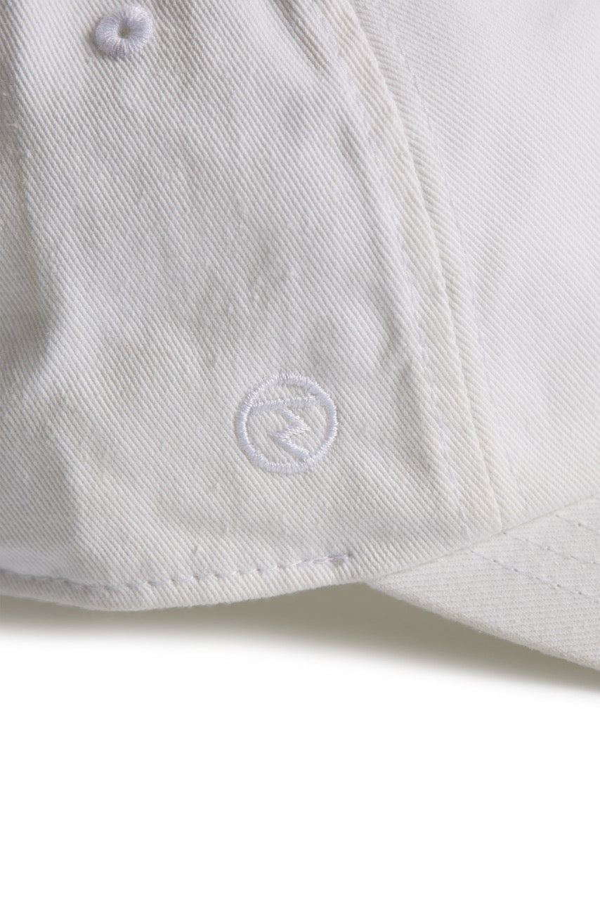 Rex Club | A close-up of the MTRC - White cap by Rex Club highlights its textured fabric and detailed stitching. Featuring a small, circular embroidered logo near the brim, this cap stands out as a distinctive piece of Manchester Tennis & Racquets Club merchandise. | Custom Caps | Custom Hats | Team Headwear | UK