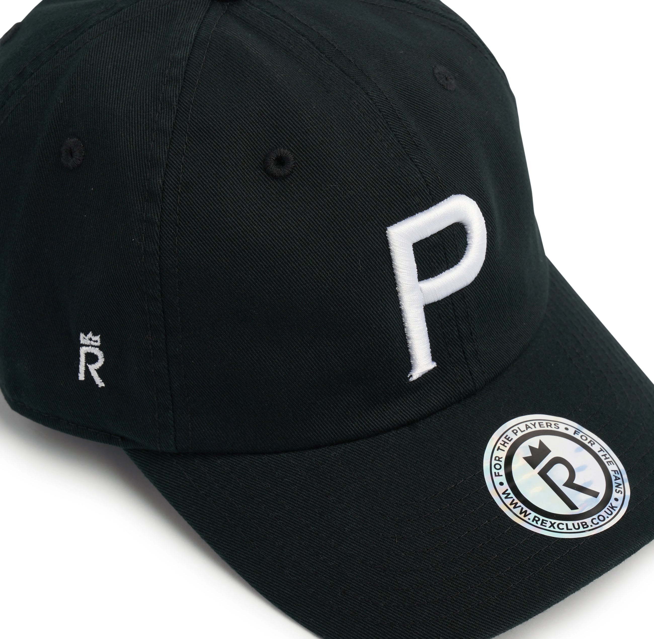 Rex Club | The Cornish Pirates - P Slouch by Rex Club is a black cap with a bold white "P" on the front, a small crowned "R" on the side, and a silver "REXCLUB.COM" sticker—bringing Champ Rugby spirit and Cornish Pirates flair to your style. | Custom Caps | Custom Hats | Team Headwear | UK