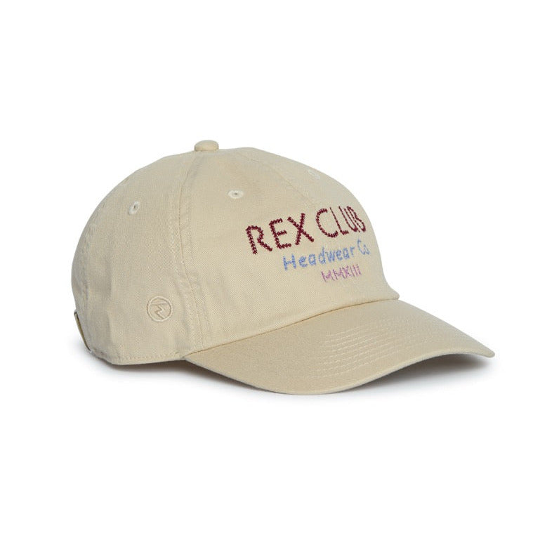 A beige baseball cap with 'REX CLUB' embroidered in red on the front, accompanied by smaller red and blue text, shown against a plain white background.