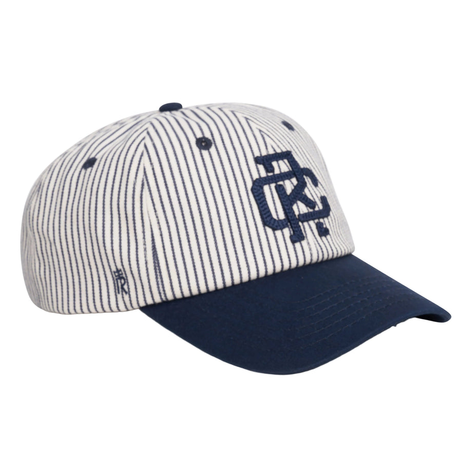 Rex Club | Introducing the RC - Baseball Pin - SS26 Navy cap by Rex Club: This white cotton baseball cap features thin navy blue vertical stripes, a solid navy blue brim, and a large embroidered logo on the front in navy. Designed for comfort with an adjustable strap, this one-size-fits-most cap combines style and versatility. | Custom Caps | Custom Hats | Team Headwear | UK