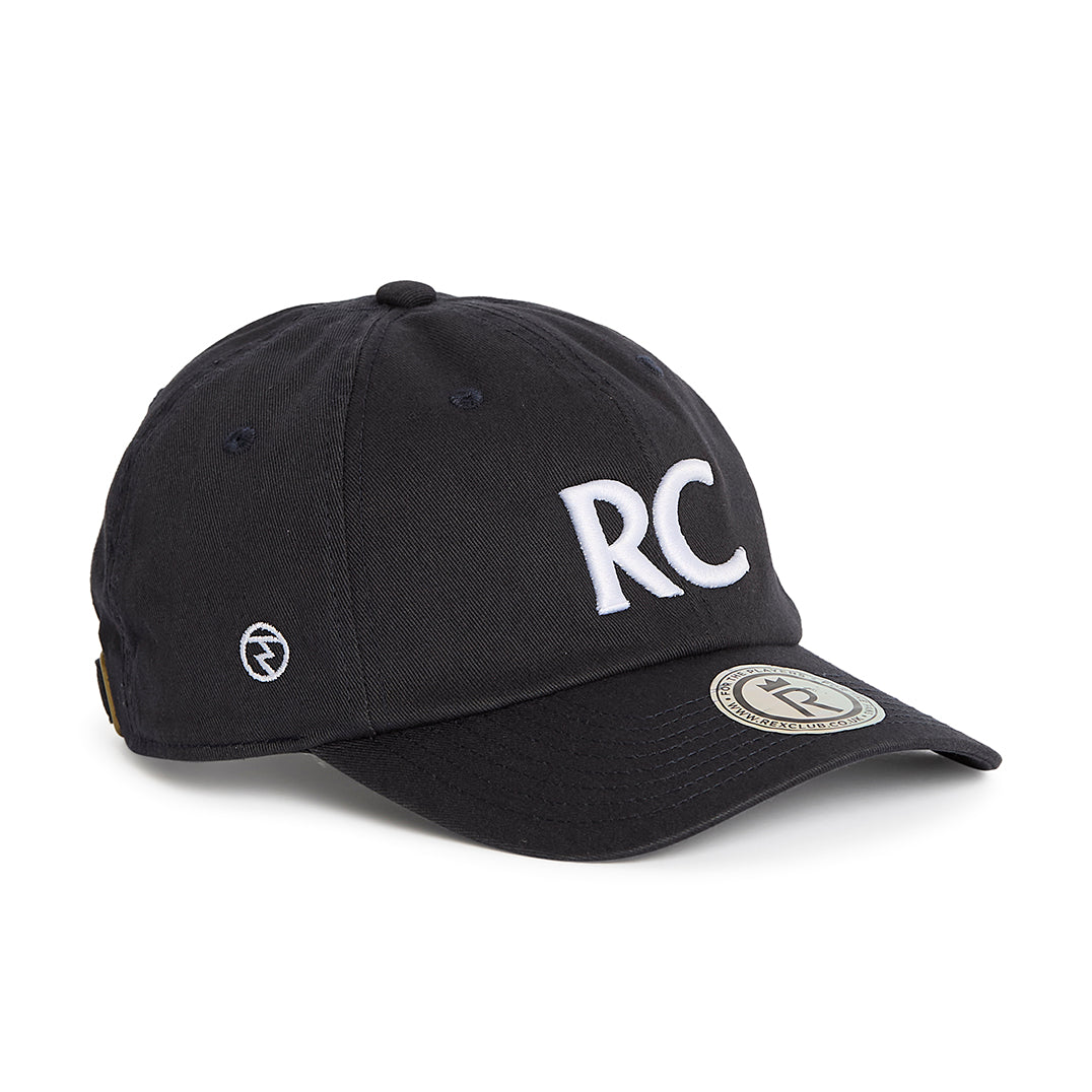 Rex Club | A navy slouch cap from Rex Club, crafted from 100% cotton, features bold white “RC” letters on the front, a round logo patch on the brim, and smaller embroidered symbols on the side for added detail. The model is named RC 3d 26. | Custom Caps | Custom Hats | Team Headwear | UK