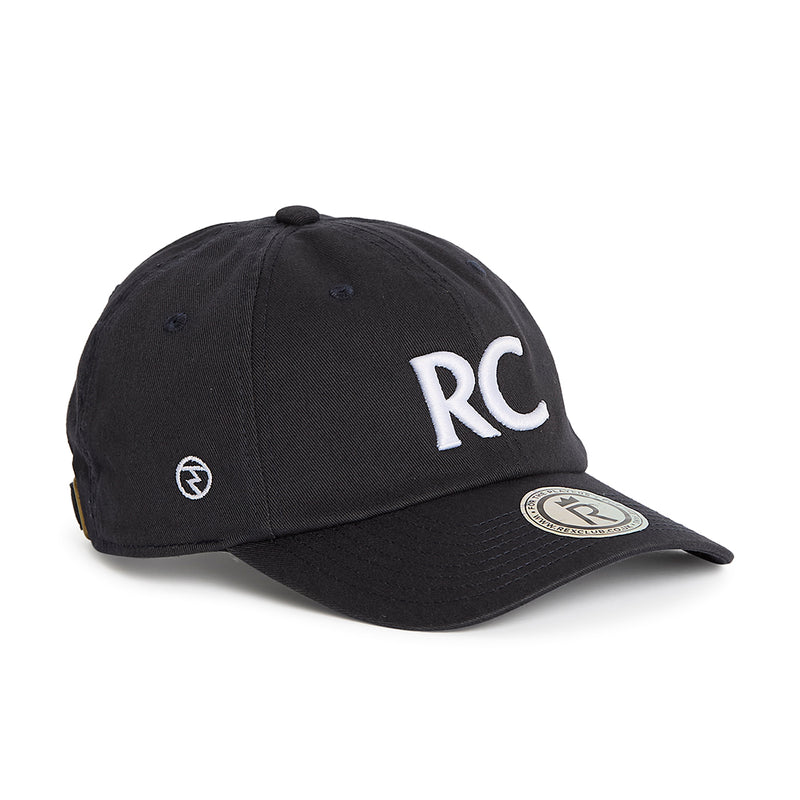 Rex Club | A navy slouch cap from Rex Club, crafted from 100% cotton, features bold white “RC” letters on the front, a round logo patch on the brim, and smaller embroidered symbols on the side for added detail. The model is named RC 3d 26. | Custom Caps | Custom Hats | Team Headwear | UK