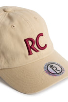 Rex Club | The RC 3d 26 - Beige by Rex Club is a beige cotton slouch cap featuring “RC” embroidered in red in 3D on the front, with a circular sticker on the brim showcasing the Rex Club logo and website. | Custom Caps | Custom Hats | Team Headwear | UK