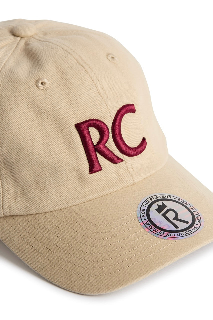 Rex Club | The RC 3d 26 - Beige by Rex Club is a beige cotton slouch cap featuring “RC” embroidered in red in 3D on the front, with a circular sticker on the brim showcasing the Rex Club logo and website. | Custom Caps | Custom Hats | Team Headwear | UK