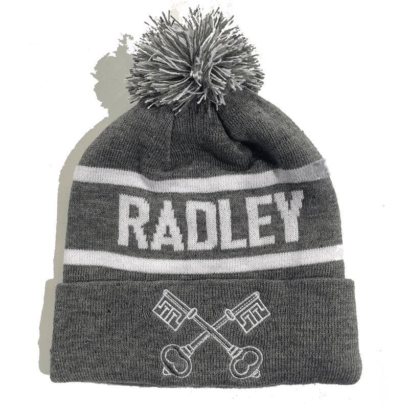 Rex Club | The Radley Bobble Hat by Rex Club is a gray knit beanie with a white and gray pom-pom, "RADLEY" in bold white letters, and two crossed keys embroidered on the folded brim. | Custom Caps | Custom Hats | Team Headwear | UK