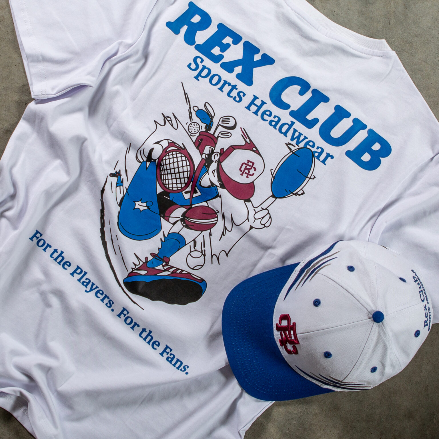 Rex Club | A white T-shirt featuring a baseball player graphic and the text "Rex the Lion" is laid flat. Below the graphic, it reads, "For the Players. For the Fans." Beside the T-shirt is a white and blue baseball cap with the same logo. | Custom Caps | Custom Hats | Team Headwear | UK