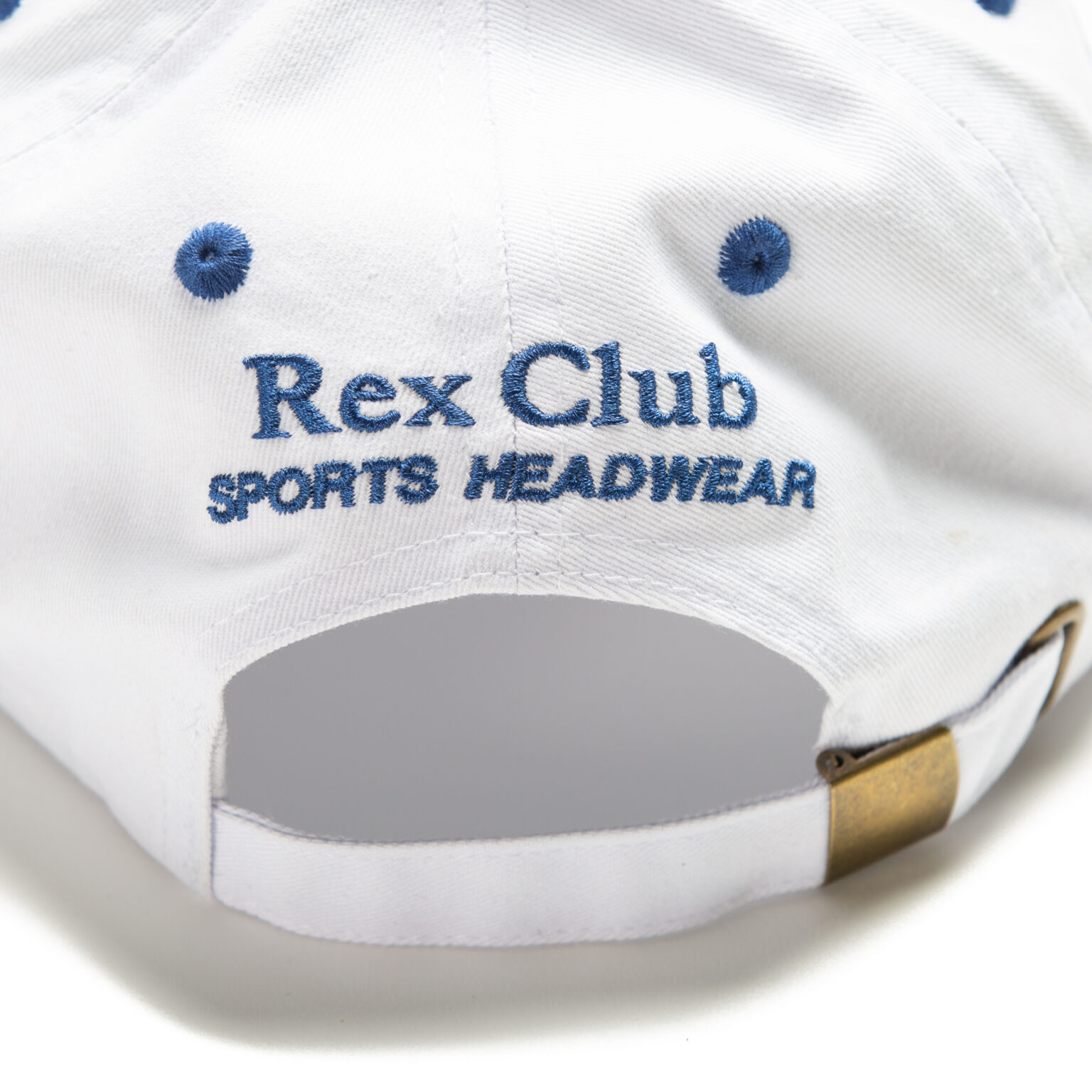 Rex Club | The image shows the back of a white baseball cap with blue embroidered text that reads "Rex Club - Summer 24 - Slouch." The cap has a brass buckle on an adjustable strap and two blue ventilation holes on either side of the text. | Custom Caps | Custom Hats | Team Headwear | UK