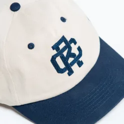 Rex Club | The Rex Club - TwoTone - Canvas Cap is a beige and navy blue baseball cap featuring a navy embroidered design on the front panel, a curved brim, and ventilation eyelets. | Custom Caps | Custom Hats | Team Headwear | UK